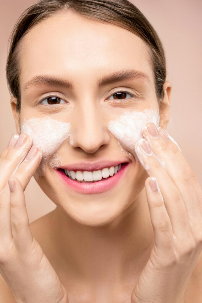 Close-up of a woman happily washing her face with foamy cleanser.